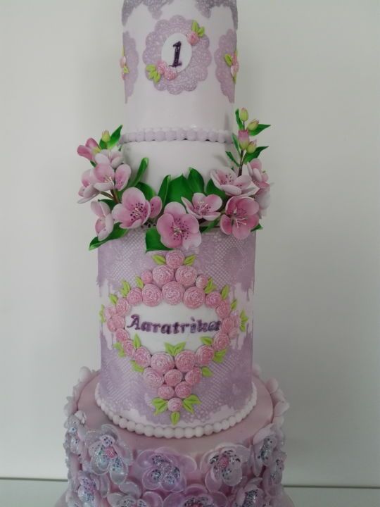 a three tiered cake decorated with flowers and the number one on it's side