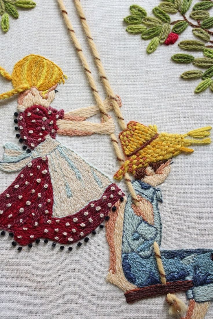 an embroidered picture of two children on a swing, one holding the string while the other is sitting down