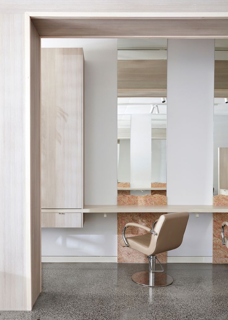 a chair sitting in front of a mirror on top of a counter next to cabinets