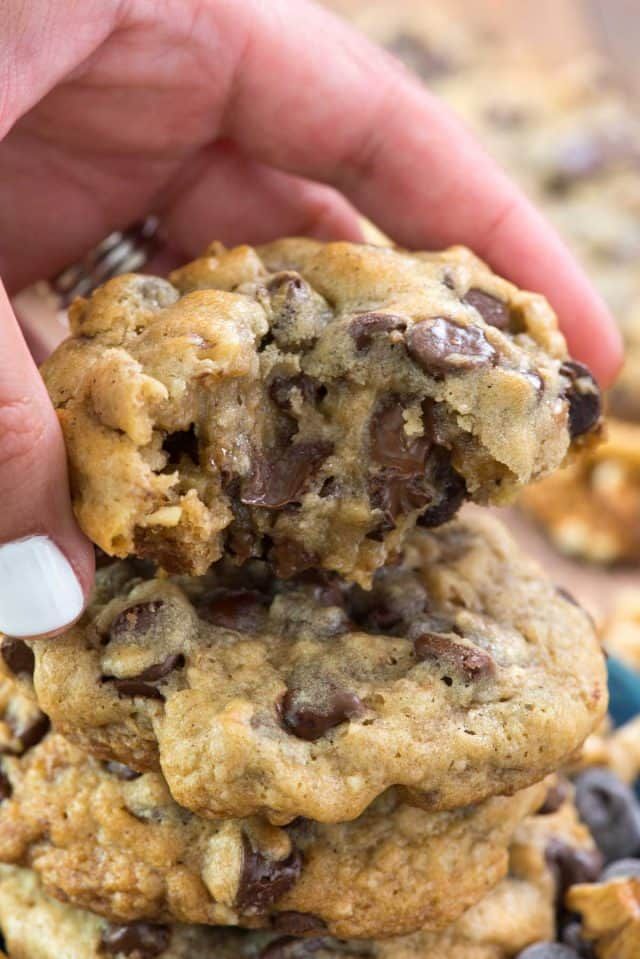 a person holding a chocolate chip cookie in their hand