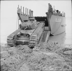 an old tank sitting in the water next to a large boat that is docked on it's side