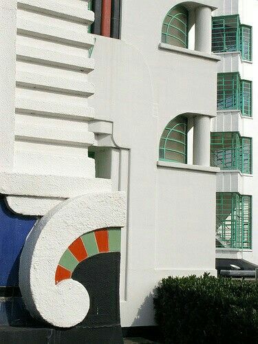 a tall white building sitting next to a lush green park