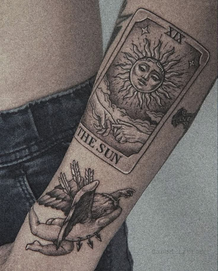 a woman's arm with a tarot card tattoo on it and the sun