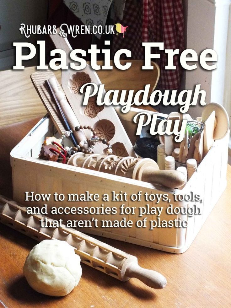 a wooden table topped with an open box filled with play dough and other toy items