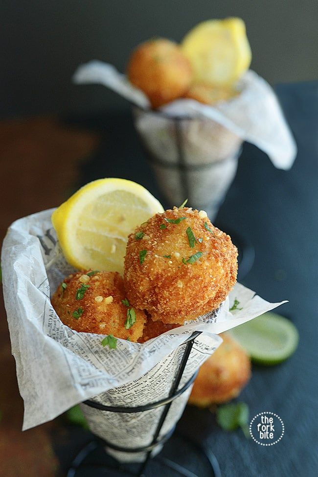 two small baskets filled with fried food next to lemons and lime wedges on a table