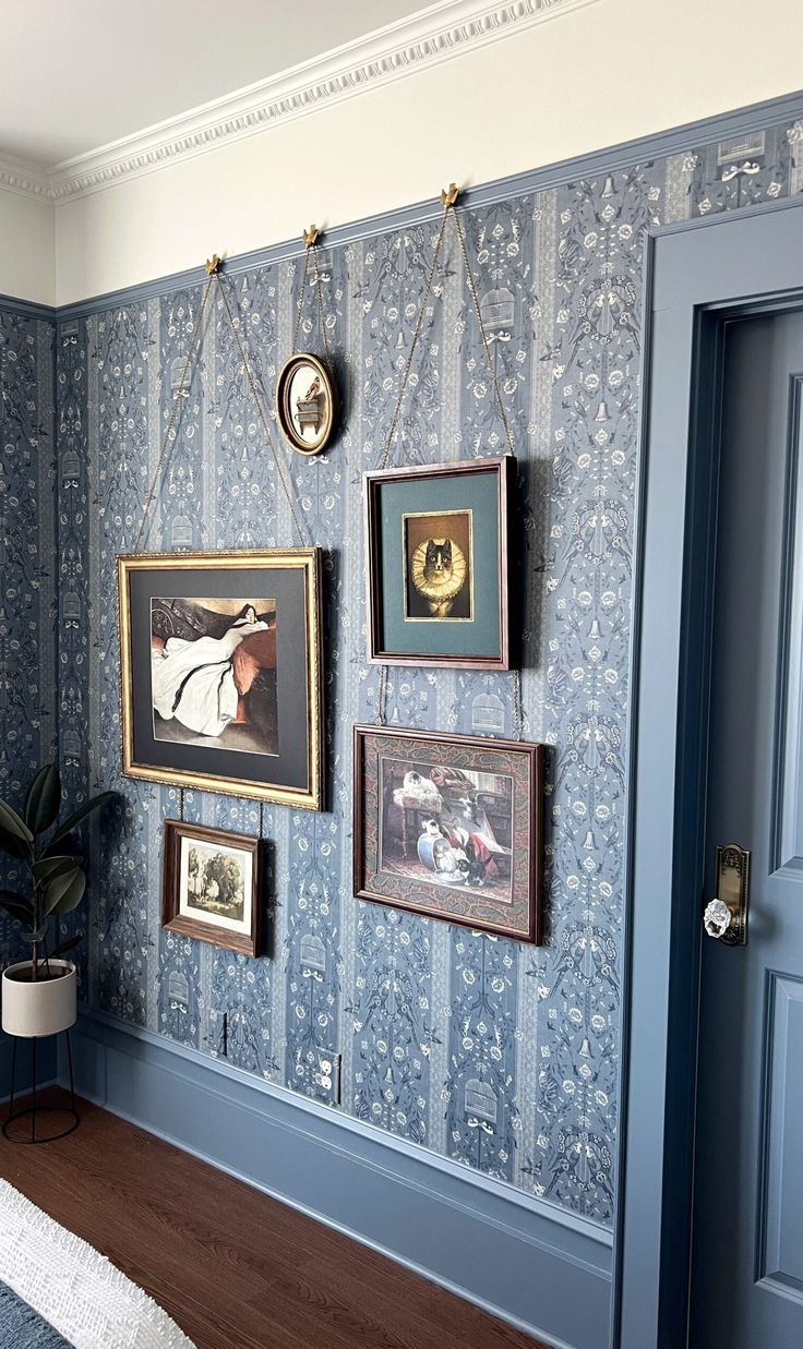 a room with blue walls and pictures hanging on it's wall, next to a door