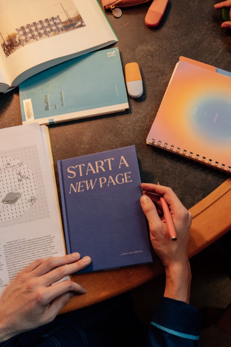 a person sitting at a table with an open book on it's lap and several other items around them