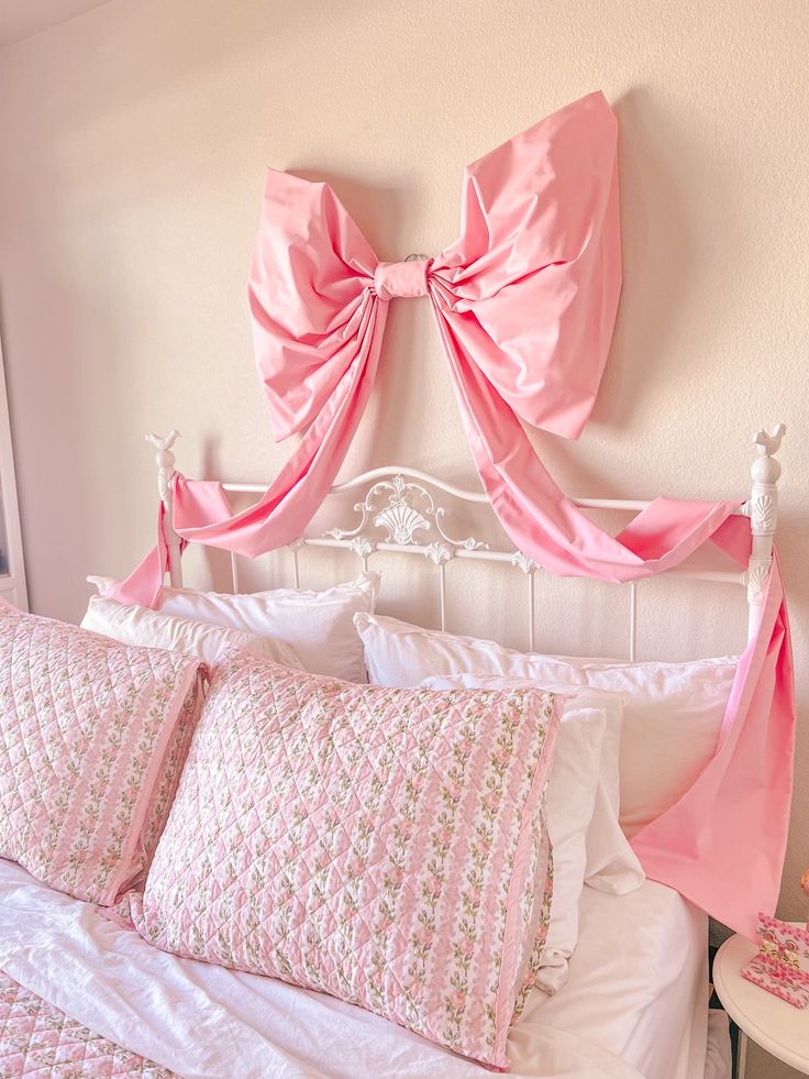 a bed with pink bows on the headboard and pillows in front of it,