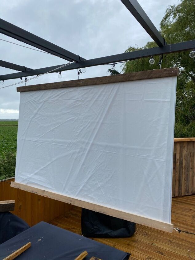 an outdoor projector screen is set up on a wooden deck with black tarps