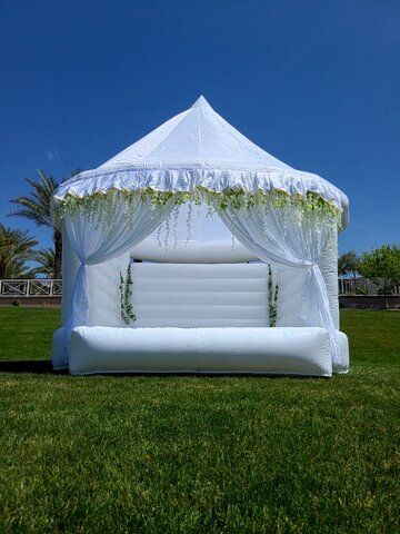 an inflatable bed is set up on the lawn for a wedding reception with white drapes and greenery