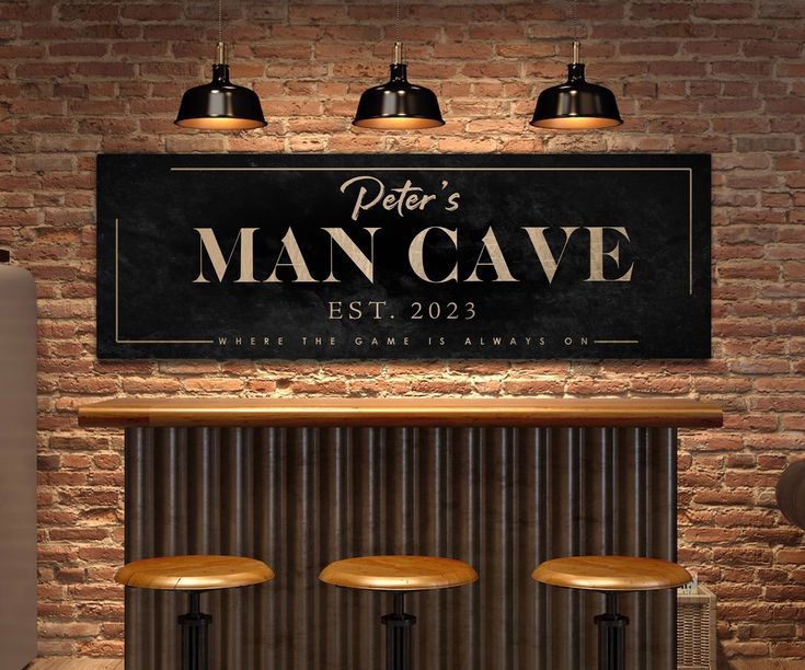 a man cave sign above three stools in front of a brick wall with lights