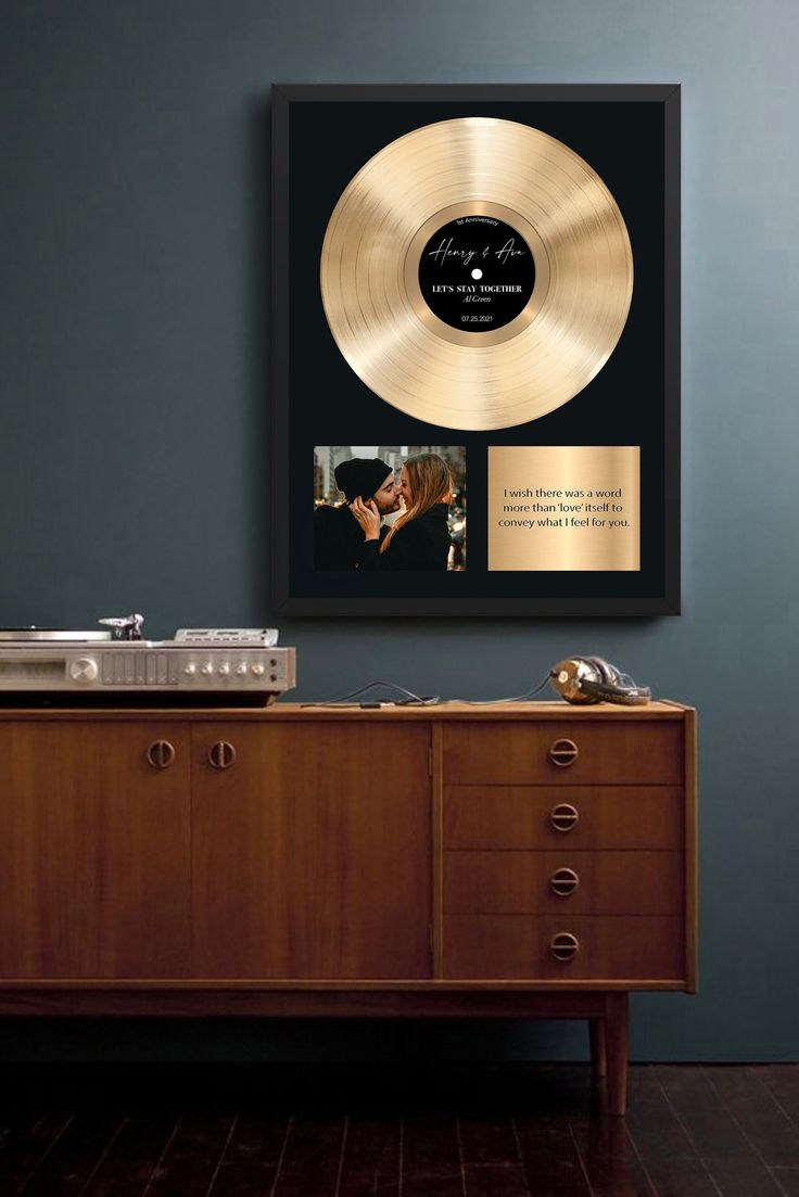 a record player sitting on top of a wooden cabinet next to a wall mounted album