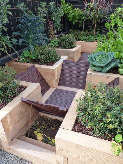 a wooden bench sitting in the middle of a garden filled with lots of different types of plants