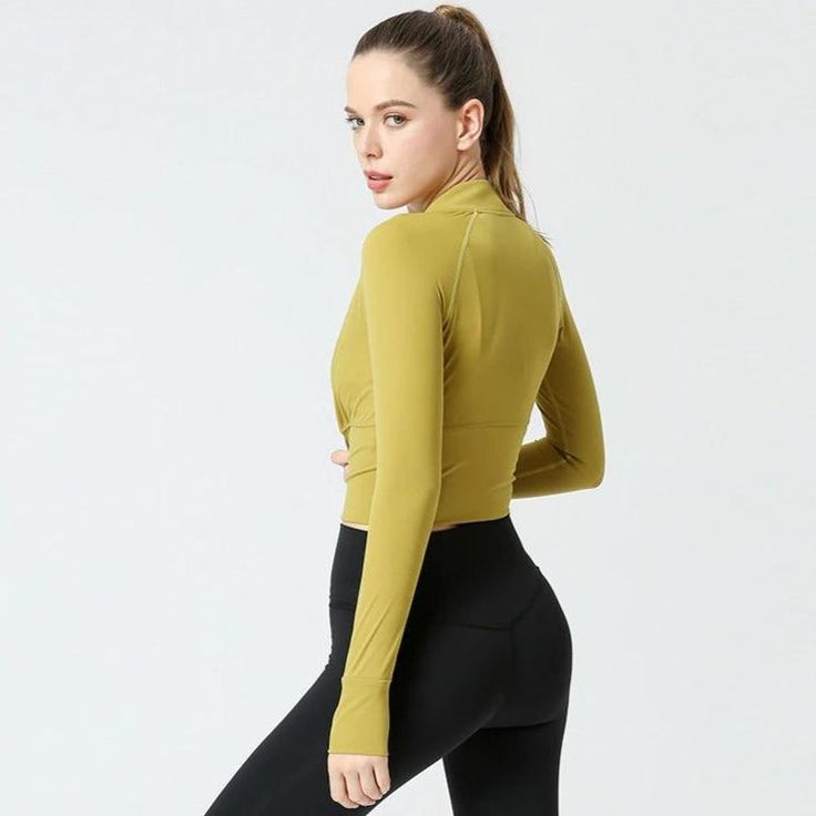 a woman in tight black pants and a yellow top is posing for the camera with her hands on her hips