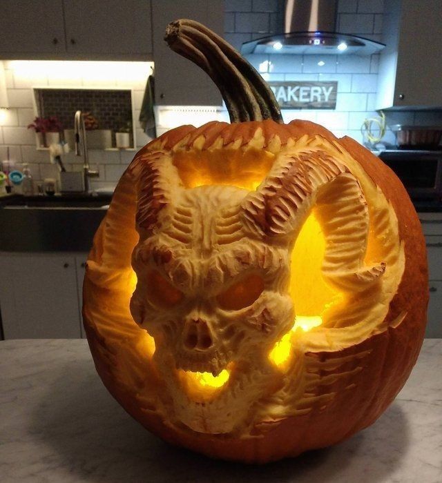 a carved pumpkin with a demon head on it