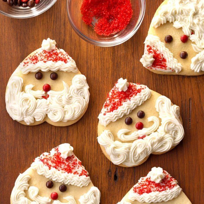 decorated cookies with white frosting and red sprinkles on a wooden table