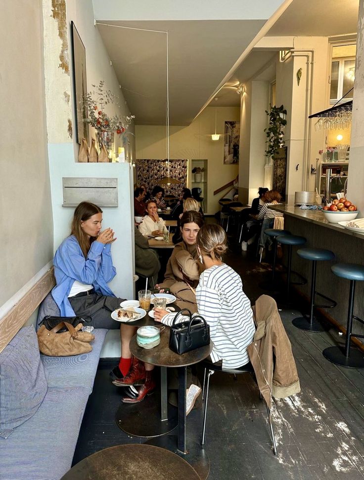 several people sitting at tables in a small room with food on the table and one person eating