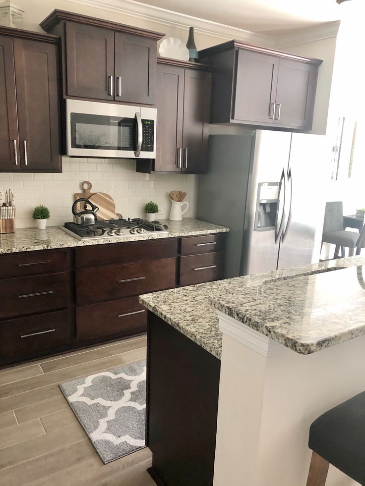 a kitchen with granite counter tops and dark wood cabinets, along with an island in the middle