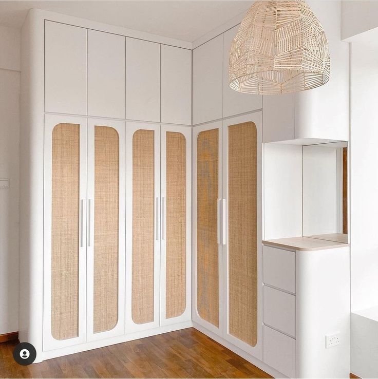 an empty room with white cabinets and wooden flooring on the wall, next to a hanging light fixture