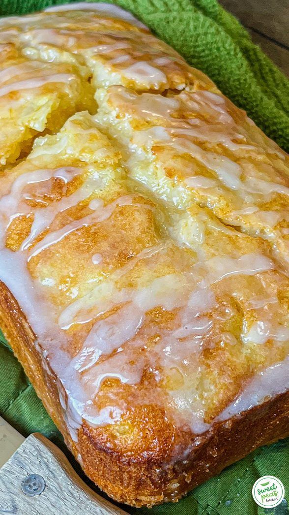 a loaf of lemon pound cake with icing on a green cloth next to a knife