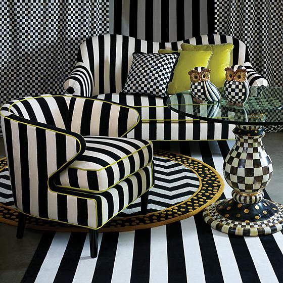 a black and white striped living room with two chairs, a coffee table and vases