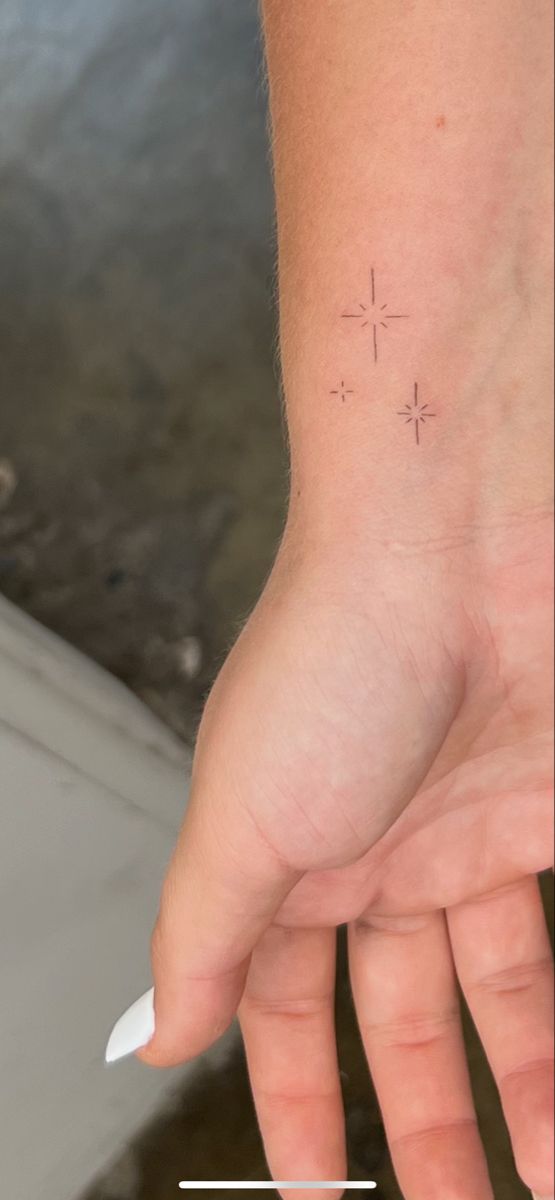 a person's hand with a small cross tattoo on it