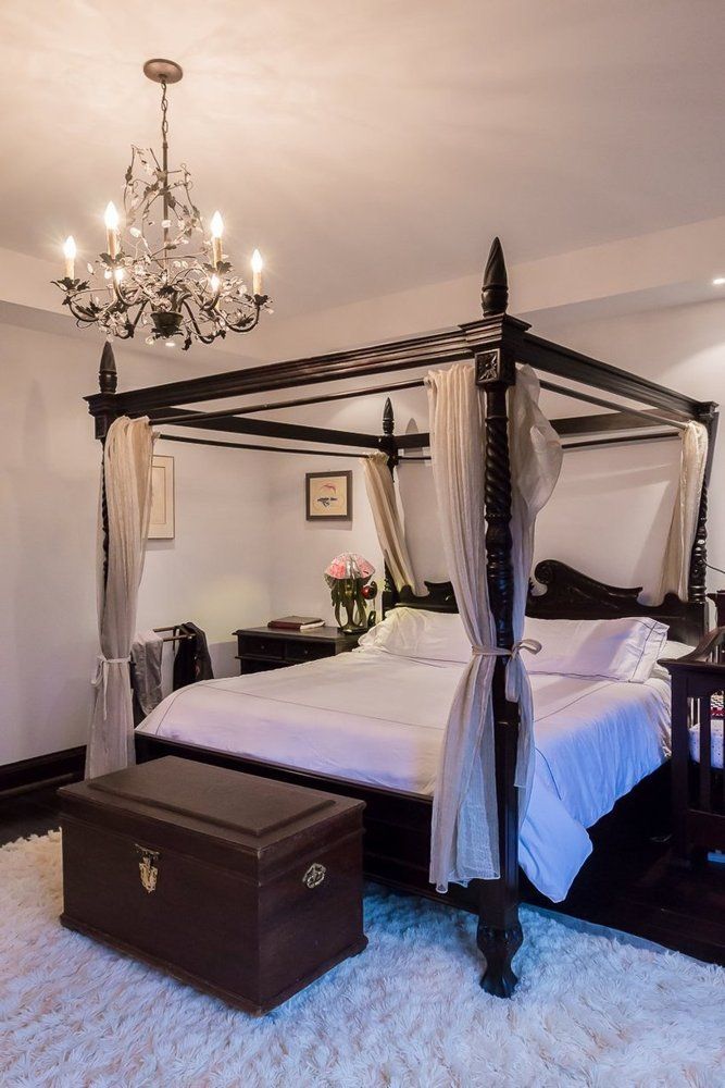 a bedroom with a canopy bed, chandelier and white carpeted flooring