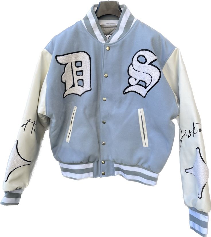 A varsity bomber jacket is a type of outerwear that is typically associated with American collegiate and sports culture. It draws inspiration from traditional letterman jackets worn by varsity athletes. The jacket is characterized by its casual and athletic design, often featuring a snap-button front closure, ribbed collar, cuffs, and waistband. The varsity bomber jacket is usually made of durable materials such as wool or nylon, providing warmth and protection from the elements. The body of the Hooded Varsity Jacket With Letter Embroidery For Fall, Fall Hooded Varsity Jacket With Letter Embroidery, Long Sleeve Varsity Jacket With Letter Embroidery For Streetwear, Long Sleeve Varsity Jacket With Letter Embroidery, Cotton Outerwear For Streetwear During Baseball Season, Long Sleeve Varsity Jacket For Sports Season Streetwear, White Varsity Jacket With Embroidered Logo For Streetwear, Sporty Streetwear Outerwear With Letter Embroidery, White Hip Hop Outerwear With Baseball Collar