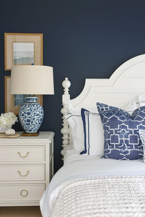 a white bed with blue and white pillows on top of it next to a night stand