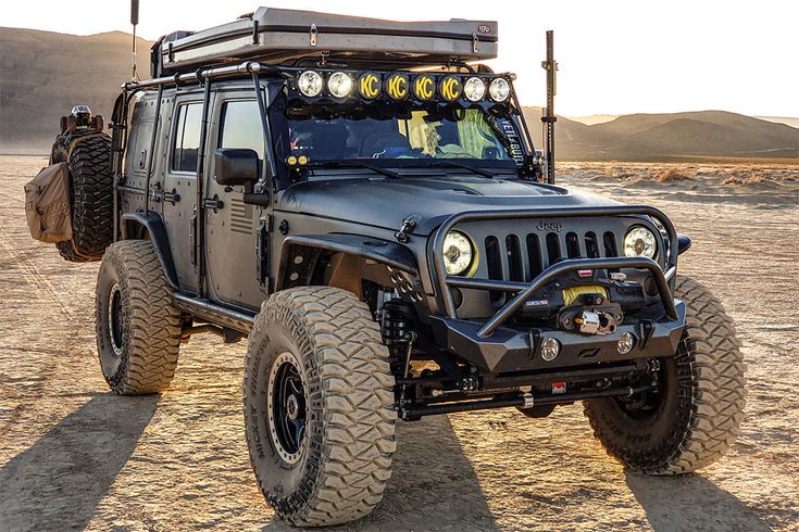 the jeep is parked in the desert with its lights on and it's hood up