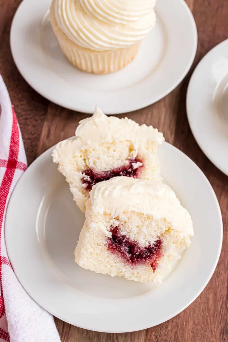 two cupcakes with white frosting are on plates