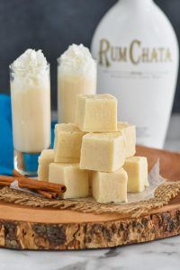 two bottles of rum and some sugar cubes on a cutting board with cinnamon sticks