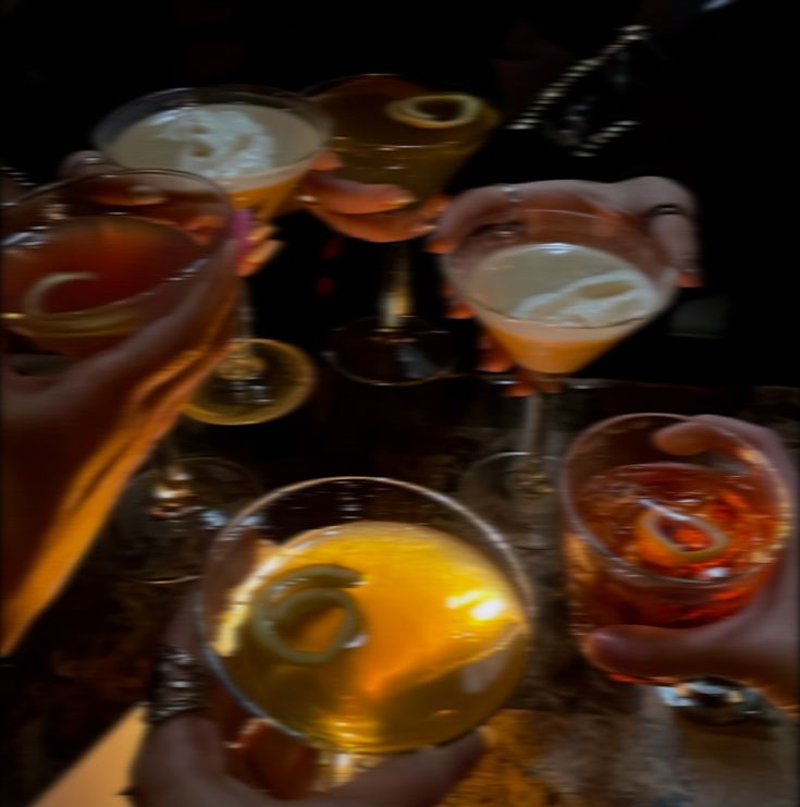 several people are holding glasses with drinks in them