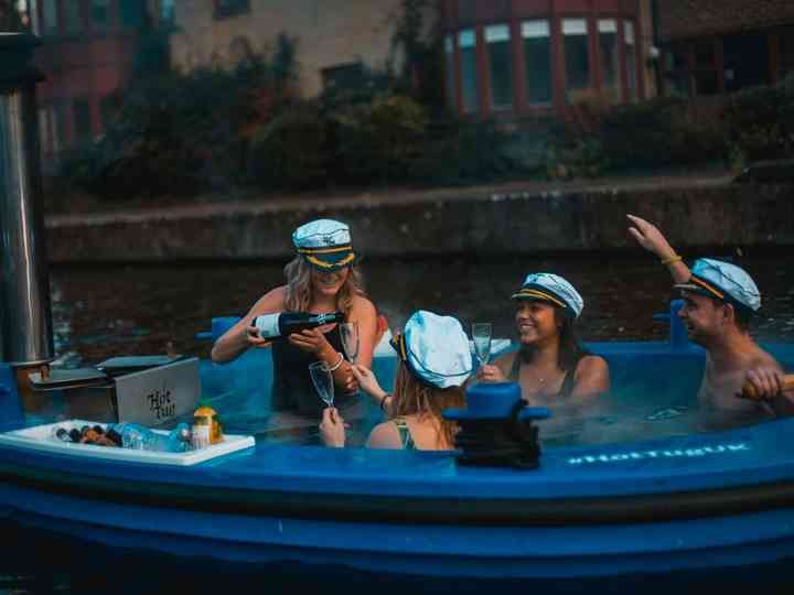 three people in a blue boat with hats on and one person taking a photo from the side