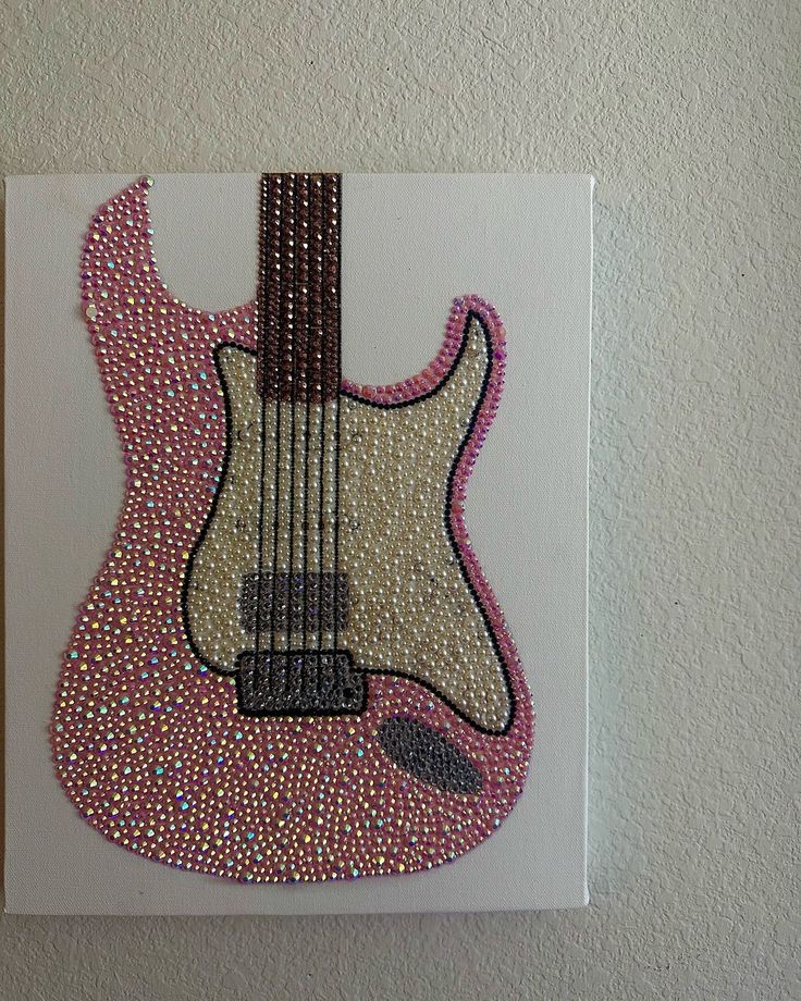 a painting of a guitar with pink and white beads on it's body is hanging on the wall