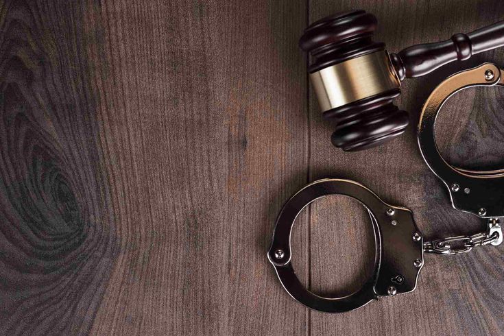 a judge's gaven and handcuffs on a wooden table