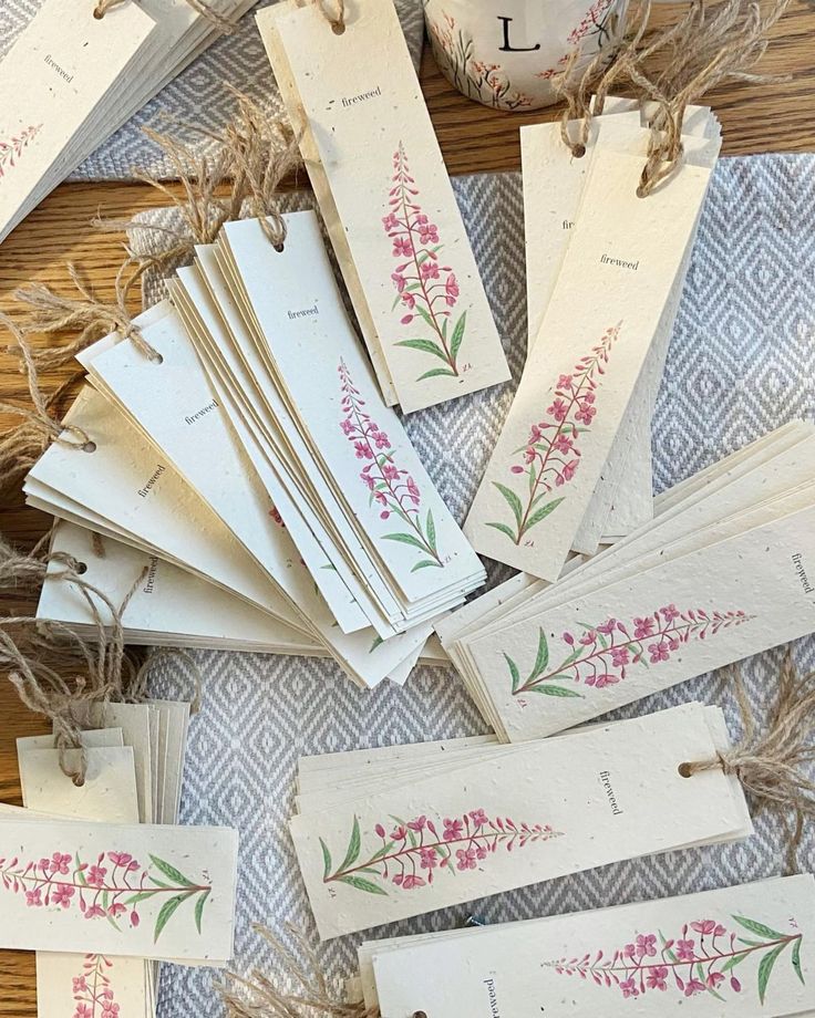 several tags with pink flowers on them sitting on a table next to some twine