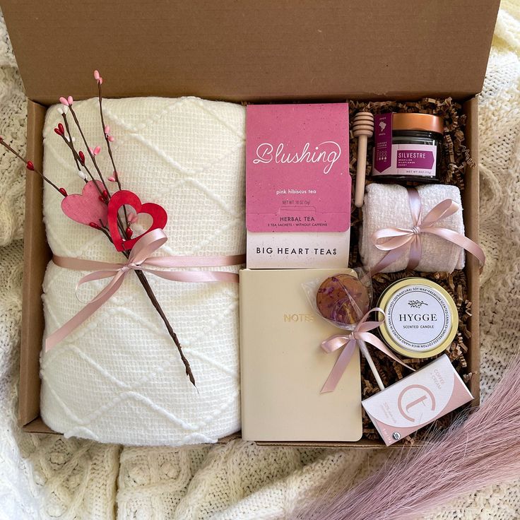 a gift box with soaps, candles and other items in it on a bed