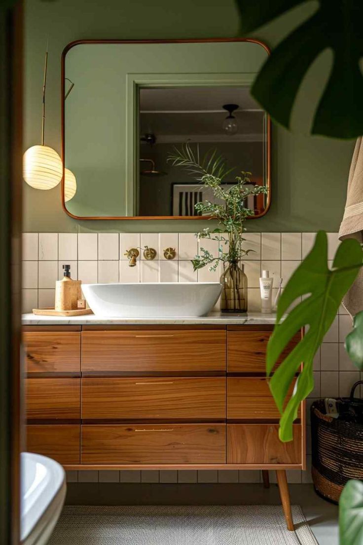 a bathroom with green walls and white tile on the floor, along with a large mirror above the sink