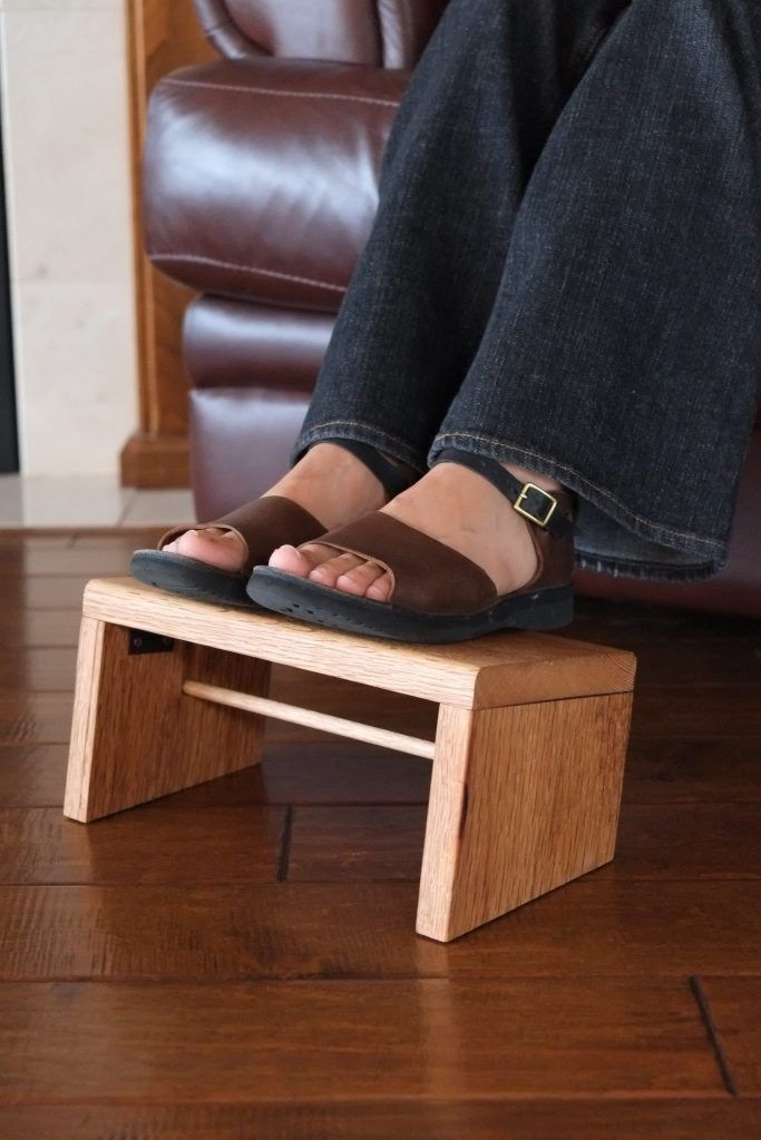 a person sitting on top of a wooden bench in front of a brown leather chair