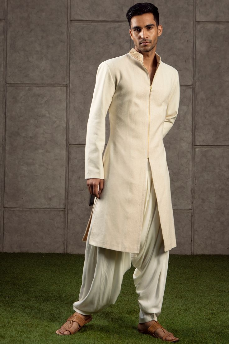 Featuring an ivory and gold top stitch sherwani in matka silk base with zari embroidered collar. It is paired with a matching kurta and patiala pants in rayon base.  FIT: True to size. COMPOSITION: Matka silk, Rayon. CARE: Dry clean only. Patiala Salwar Suits, Wedding Kurta For Men, Embroidered Sherwani, Sherwani Groom, Sherwani For Men, Indian Bride Outfits, Wedding Sherwani, Dhoti Pants, Mens Casual Outfits Summer