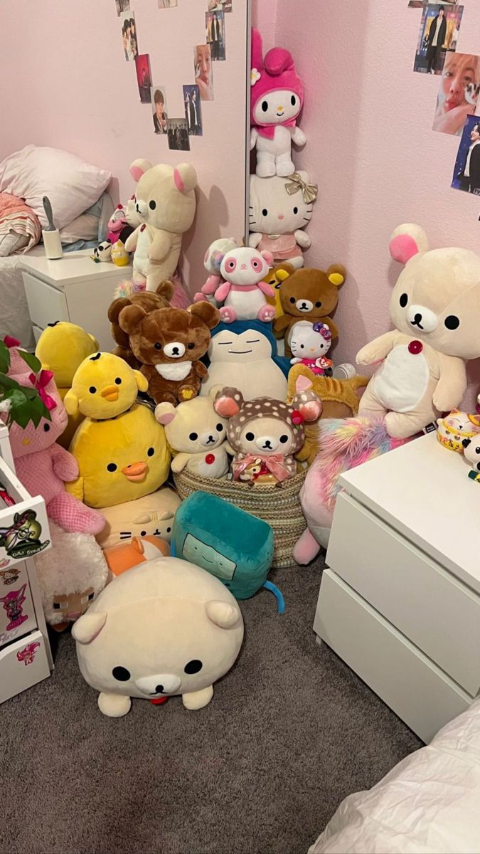 a room filled with lots of stuffed animals next to a white dresser and chest freezer