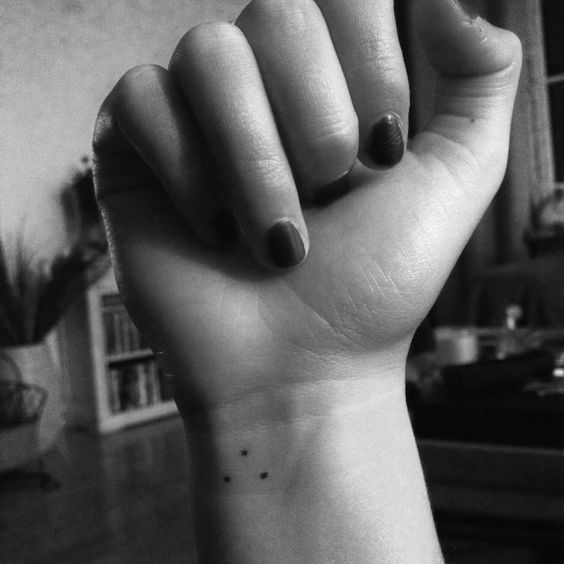 black and white photo of a woman's hand with a small tattoo on it