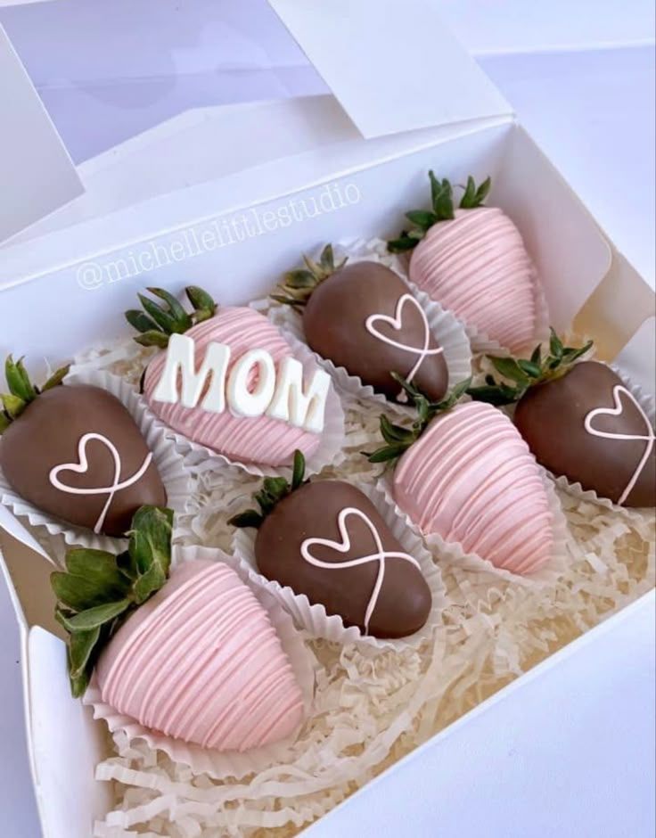 four chocolate covered strawberries in a box with the word mom written on them and hearts