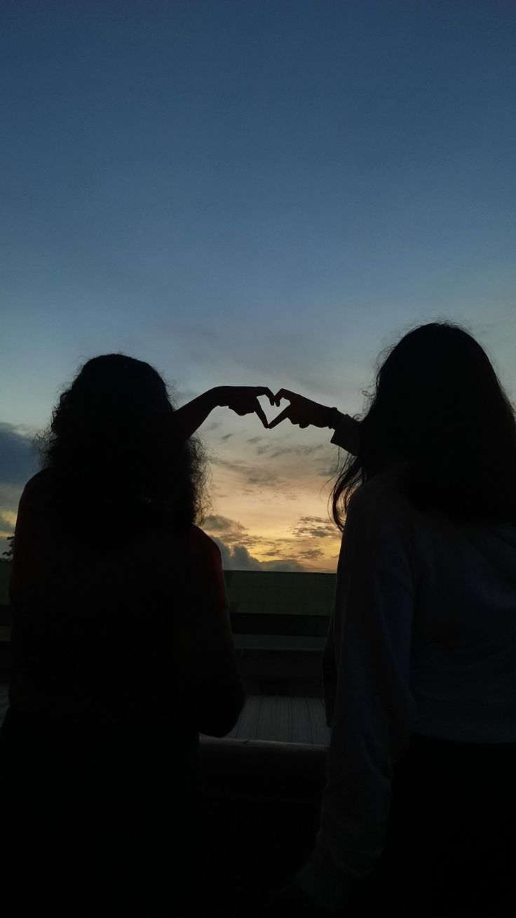 two women making a heart with their hands