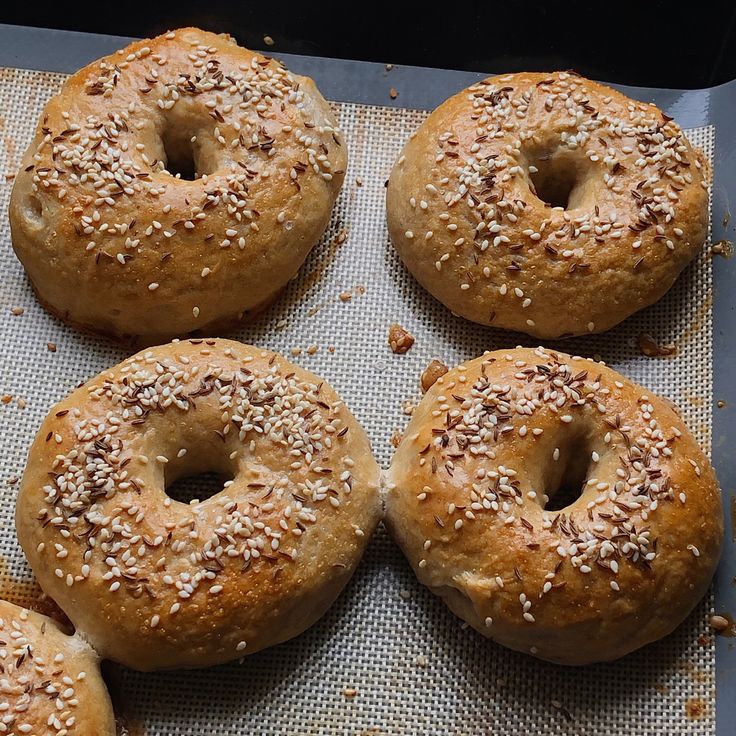 six bagels with sesame seeds on a baking sheet