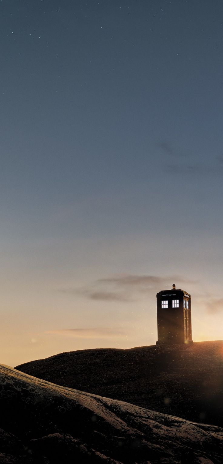 a small tower sitting on top of a hill under a sky filled with stardust