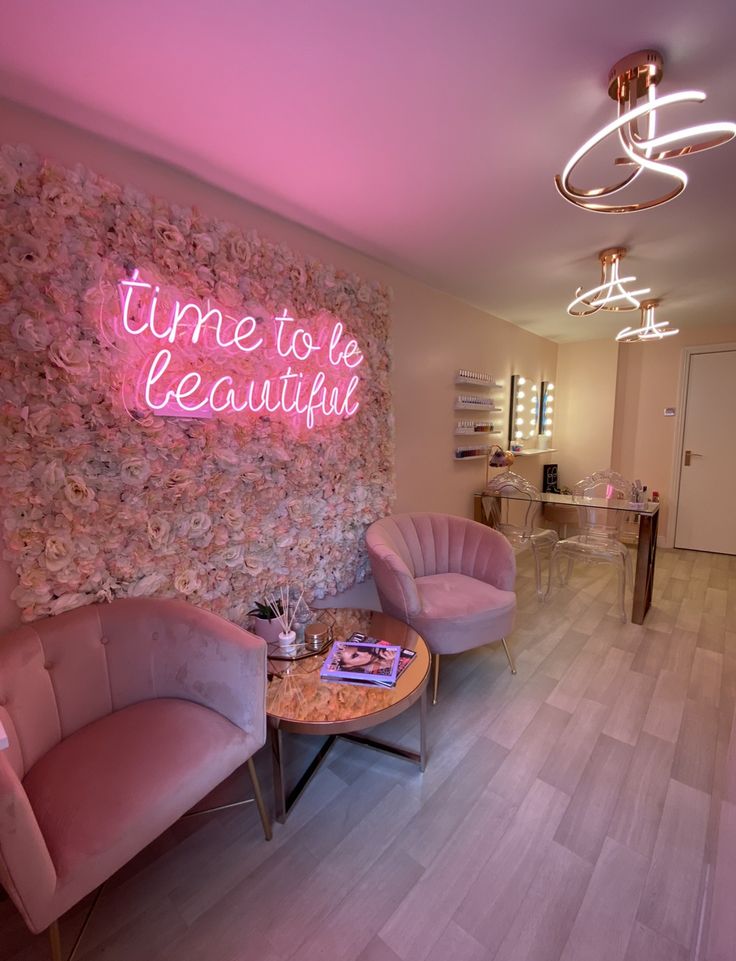 two chairs and a table in front of a wall with a neon sign that says time to be beautiful