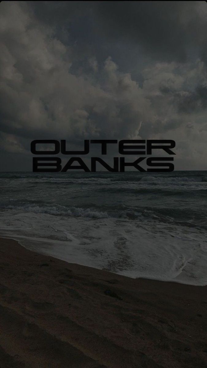 the words outer banks are written in black on a dark cloudy day at the beach