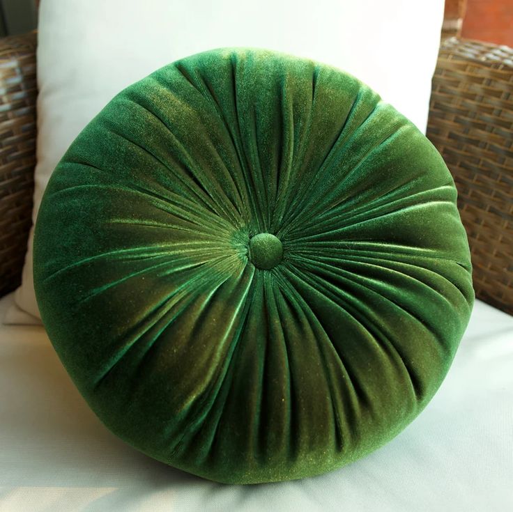 a green round pillow sitting on top of a bed